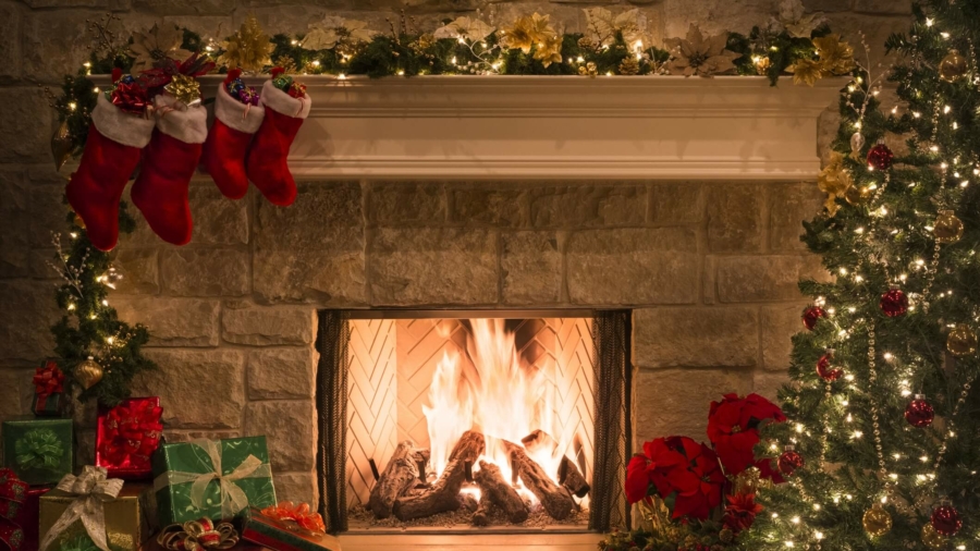 Christmas tree, gifts, stockings hanging from mantel by blazing fire in fireplace. Christmas eve.