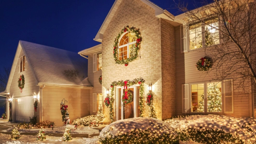 Holiday decorated home at evening with Christmas lighting, fluffy snow.